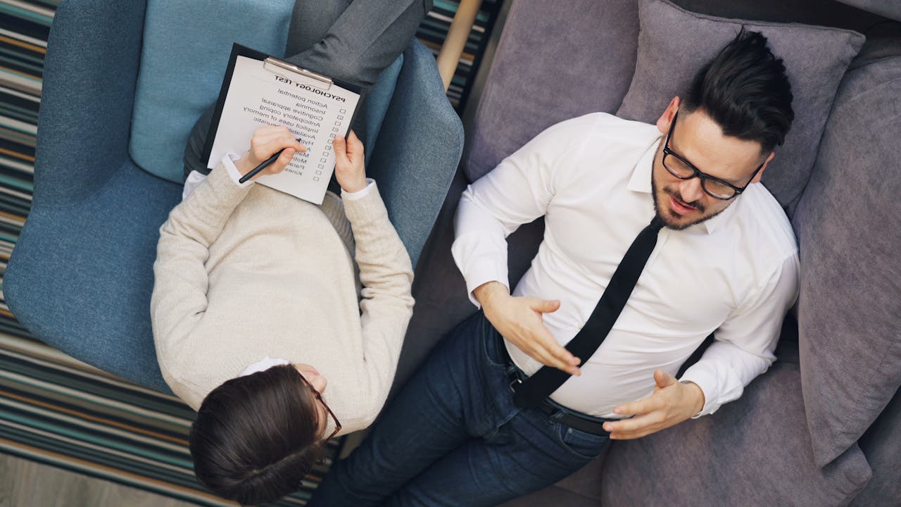 about-us Therapist takes notes while patient discusses problems on a couch during a session.