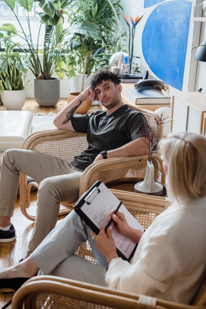 A man and a woman in a therapeutic counseling session in a plant-filled modern office space.